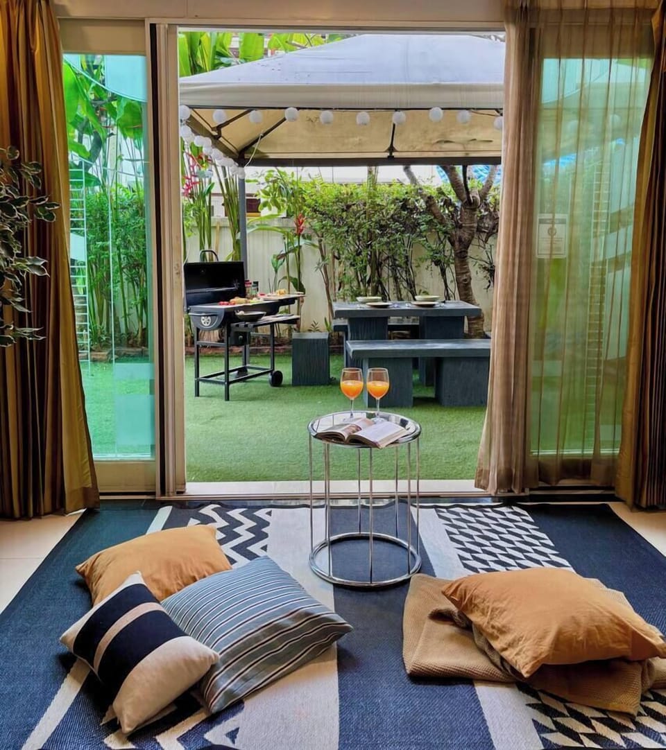 【Garden】Experience rare greenery in the city center. The living room opens to a cozy garden with a foldable mosquito net door for comfort. Move the pillows and coffee table to chill on the floor in true Thai style.