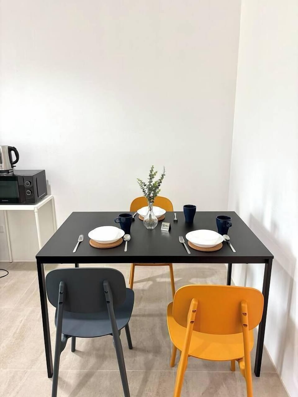 The space with a dining table along with basic kitchen essentials like cups, bowls, plates and essentials for your comfort stay.