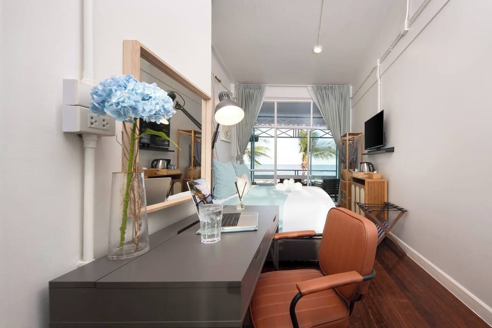Bright seafront room with balcony, workspace, and beach views