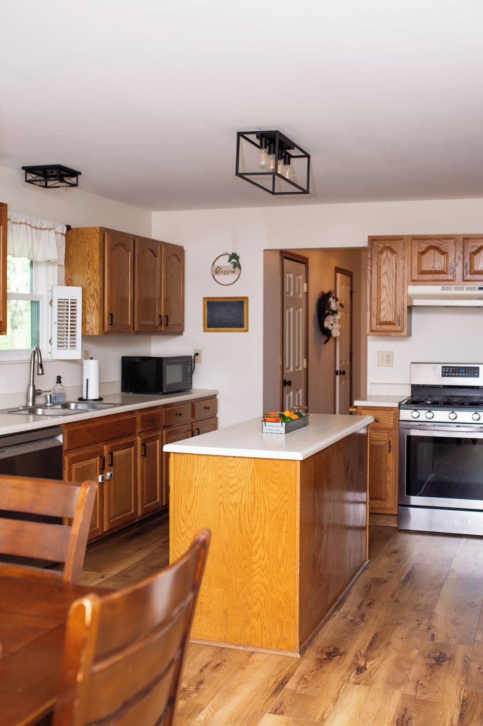 Bright farmhouse-style kitchen with island, wood cabinets, and stainless range