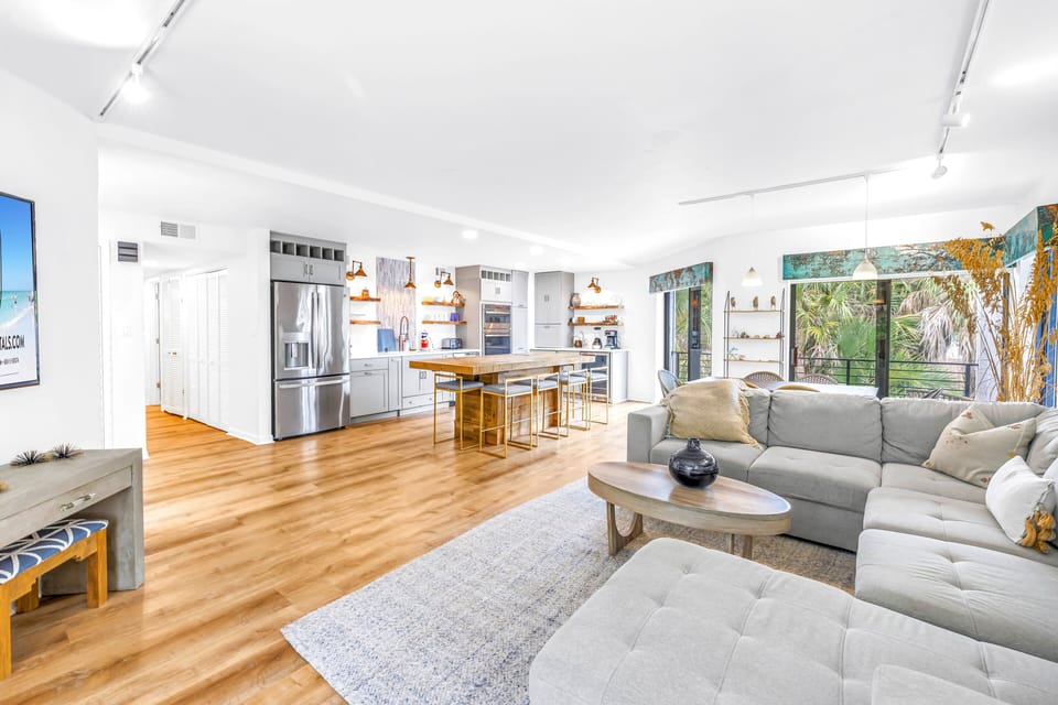 Living area spacious and sunny, opens to kitchen with tropical view.