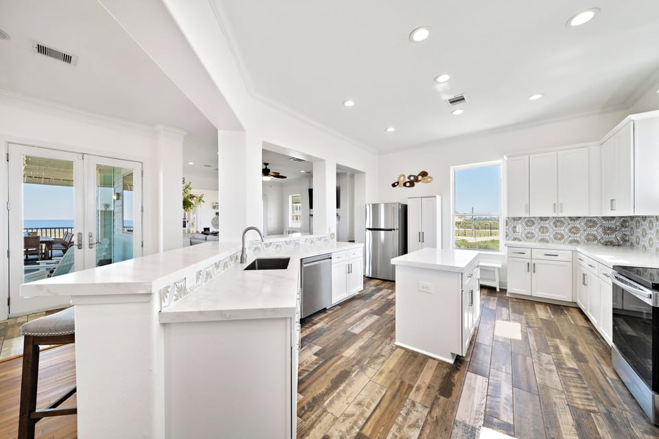 Open-concept kitchen featuring stainless steel appliances, large workspace, ample cabinetry, and coastal views. Designed for cooking and entertaining.