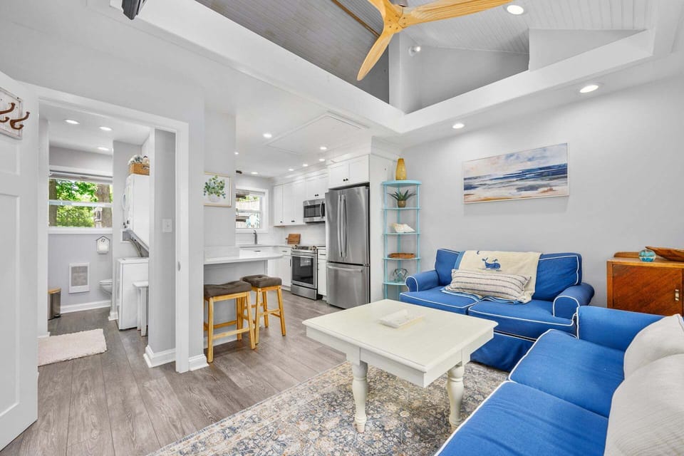 Living room flowing into the kitchen, featuring an open and connected layout that creates a spacious atmosphere for relaxing, cooking, and gathering together.
