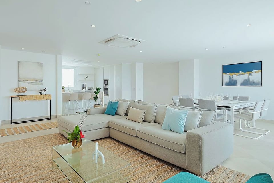 Sunlight pours into your open-plan living space, where a plush sectional invites you to unwind. The sleek kitchen and dining area flow seamlessly, perfect for entertaining or quiet evenings.
