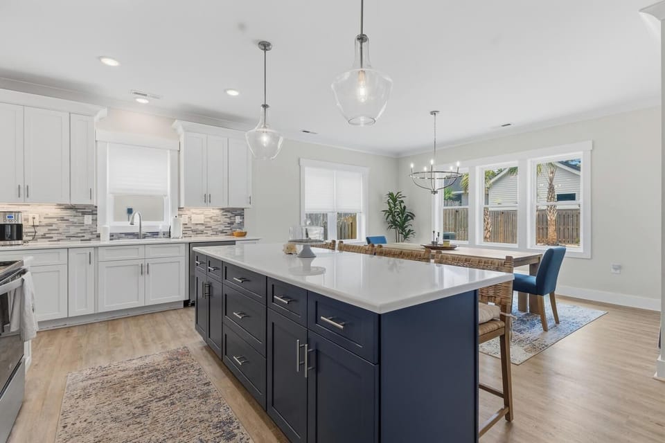 Picture yourself preparing meals in this bright, modern kitchen with a spacious island, stylish cabinetry, and natural light streaming through large windows—a perfect space for your culinary adventures.