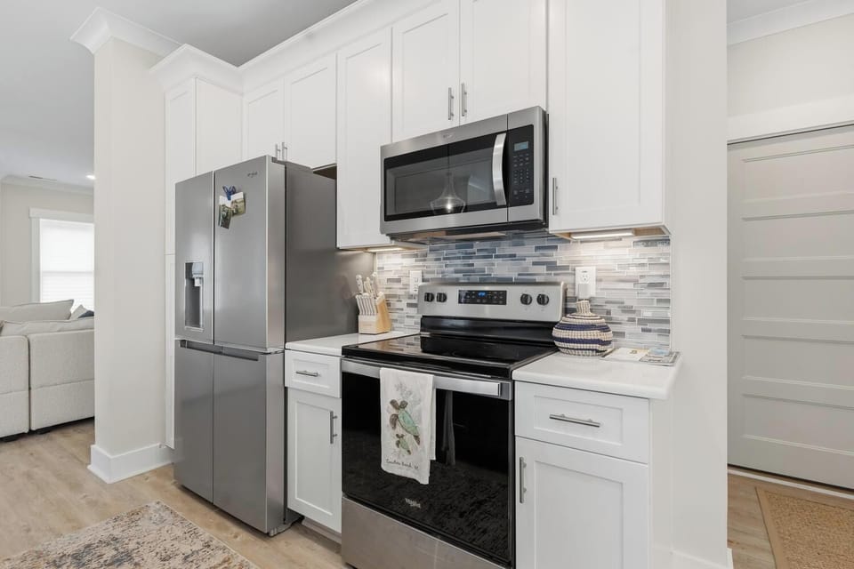 Your modern kitchen is fully equipped with stainless steel appliances, crisp white cabinetry, and elegant tile backsplash, ready for you to prepare meals during your stay.