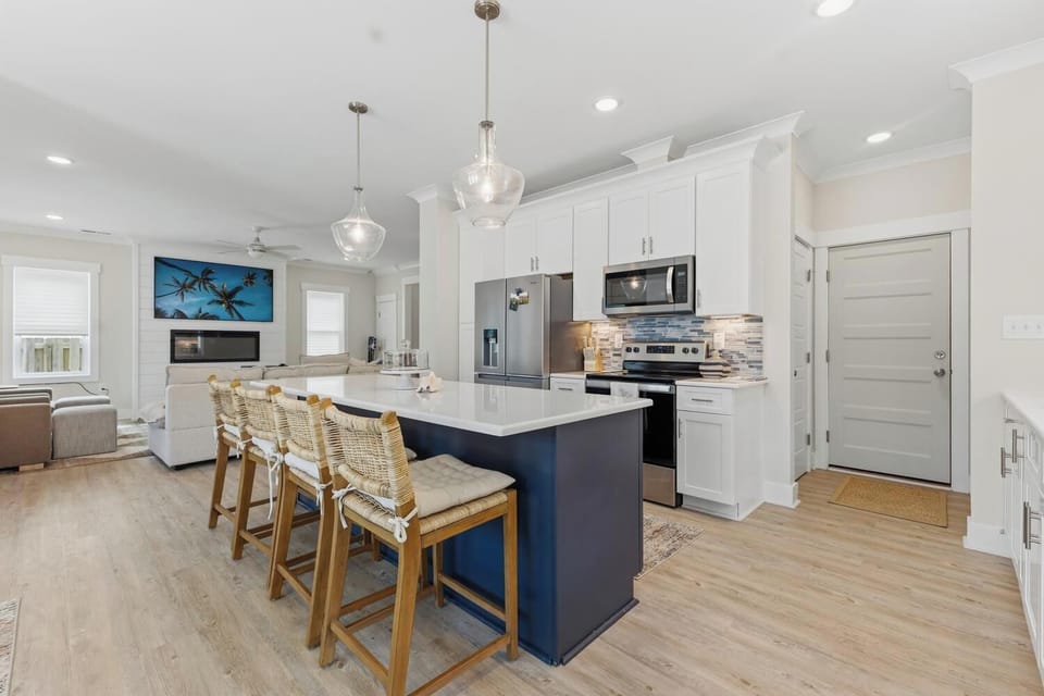 Gather around the island in your bright, open-concept kitchen where coastal charm meets modern convenience. Gleaming countertops, stainless appliances, and plenty of prep space invite you to create memorable meals together.