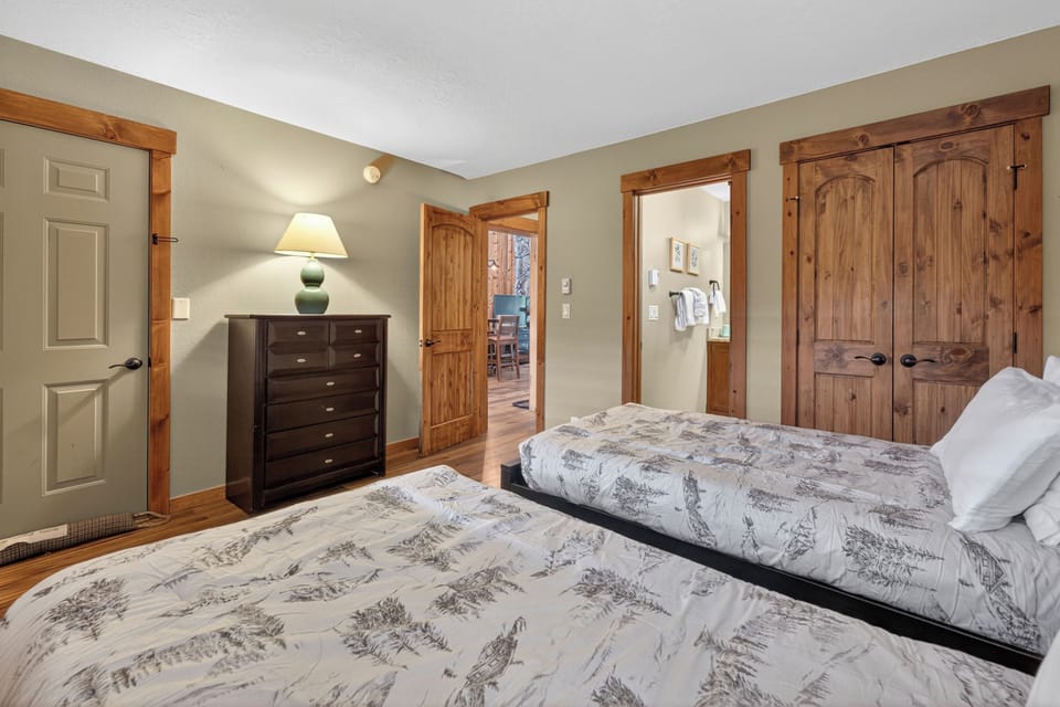 Unwind in your peaceful retreat featuring two comfortable beds, charming rustic wood details, and an inviting en-suite bathroom with plush towels waiting for you.