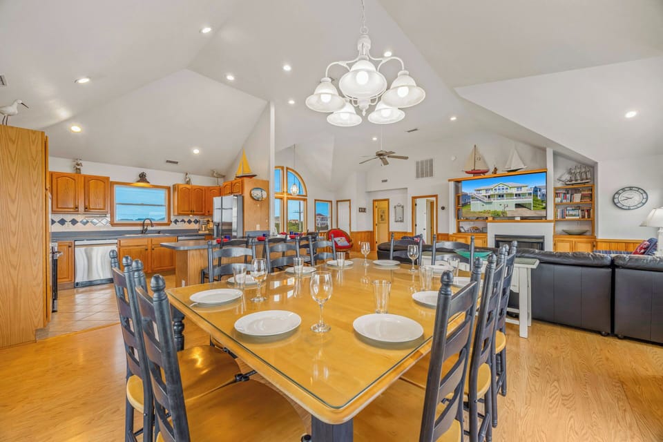 Picture yourself gathering around this spacious dining table, sharing meals with loved ones under the elegant chandelier while sunlight streams through stunning arched windows into your vacation home.