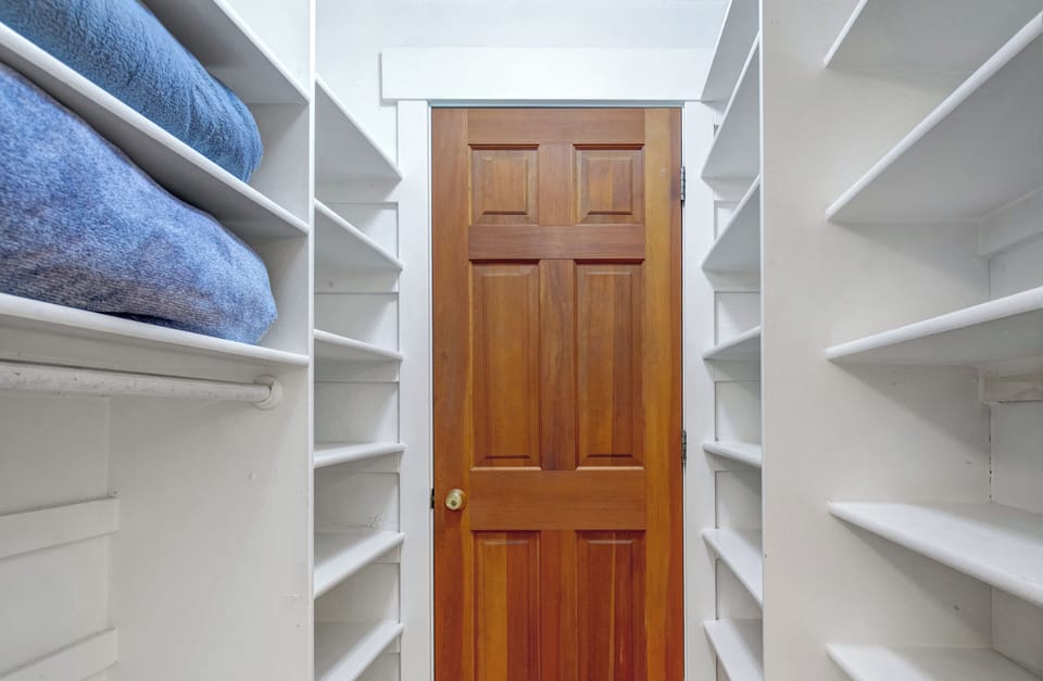 Spacious walk-in closet with custom white shelving.