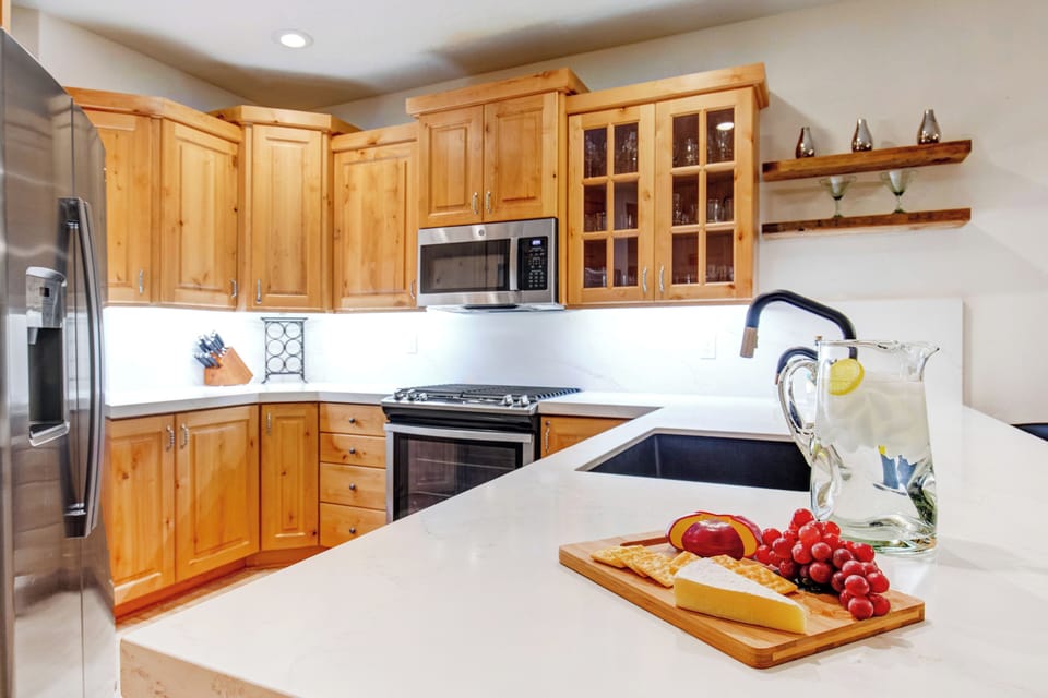 This Park City Lodging vacation rental offers a fully-equipped kitchen with white countertops and warm wood cabinetry.