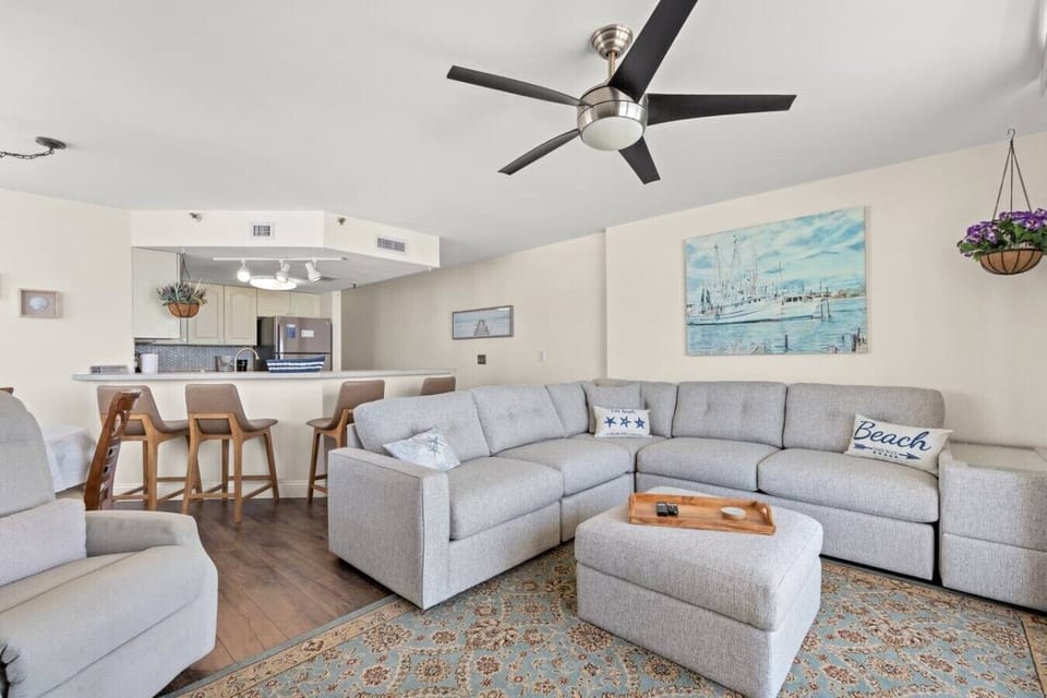 Open floor plan at The Pinnacle North Myrtle Beach Unit 506 features natural lighting, flowing living, dining, and kitchen spaces, plus a breakfast bar with seating for 4.