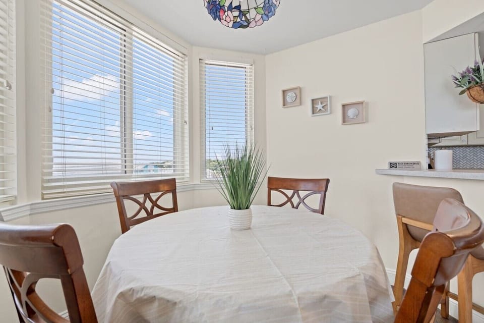 Dining area at The Pinnacle North Myrtle Beach Unit 506 features a circular dining table with seating for 4, surrounded by windows with beautiful ocean views perfect for meals or morning coffee.
