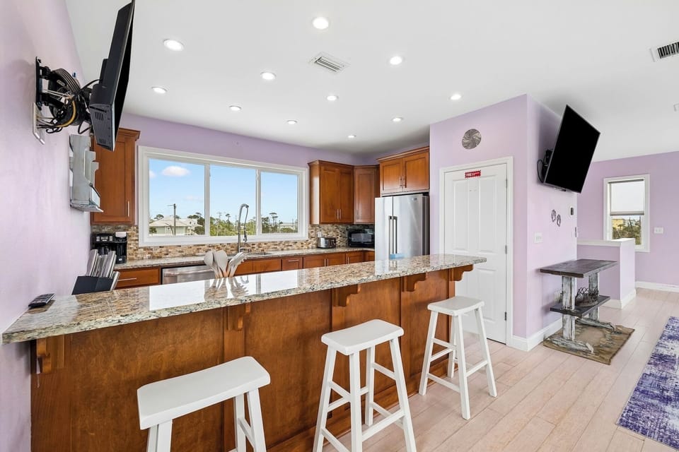 Picture yourself cooking in this spacious kitchen with granite counters, stainless appliances, and a breakfast bar perfect for morning coffee while soaking in scenic views through large windows.