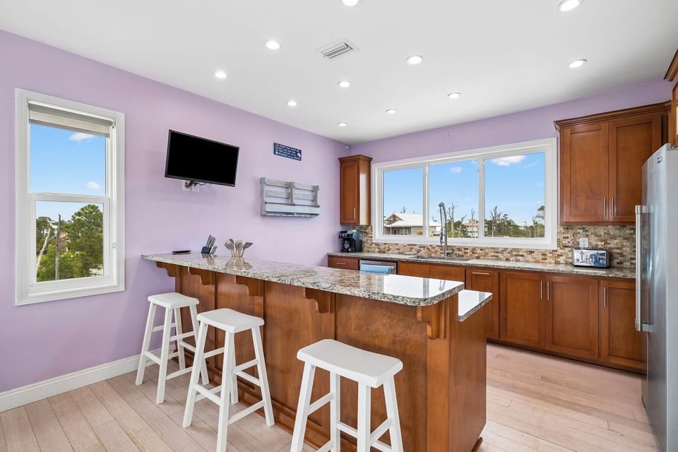 Your bright kitchen features modern appliances, granite countertops, and a convenient breakfast bar—perfect for morning coffee while enjoying natural light and peaceful views through the windows.