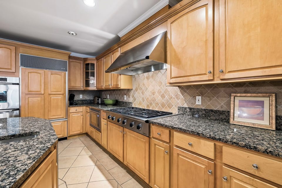 You'll love preparing meals in this spacious, well-appointed kitchen featuring granite countertops, a professional-grade gas range, and ample cabinetry for all your culinary needs.