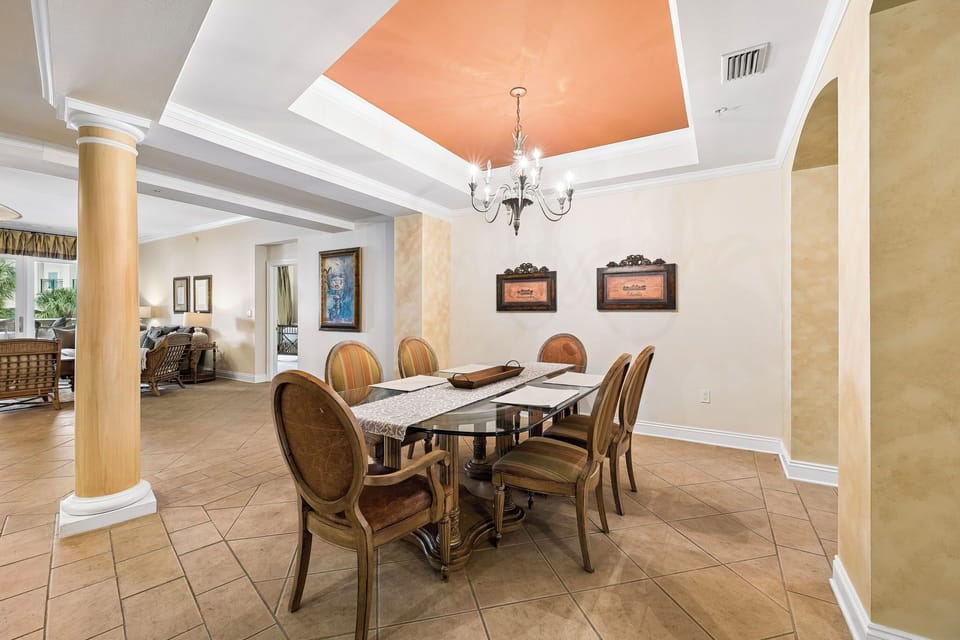 Gather around this elegant dining table beneath a statement chandelier and recessed ceiling detail—your perfect setting for memorable meals together.