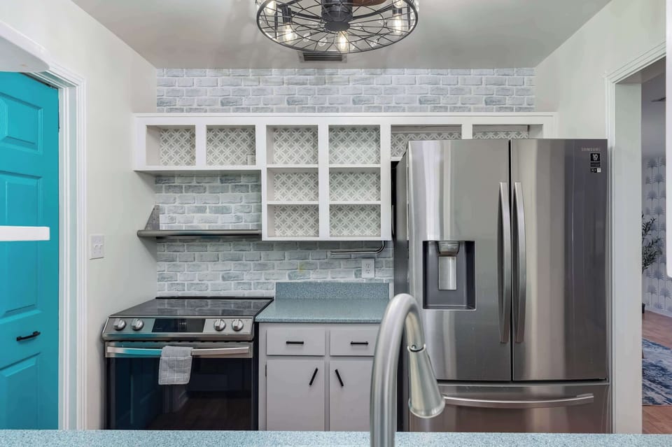 Fully equipped kitchen w/ stainless fridge, gas range & open shelving for easy cooking.
