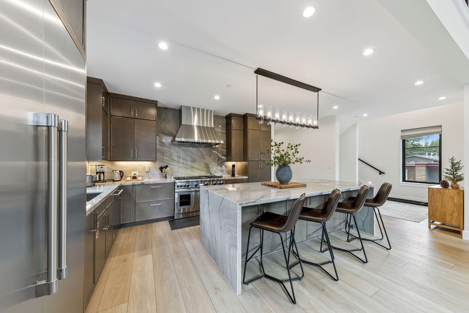 Step into your modern gourmet kitchen where sleek marble and rich wood tones invite you to create. Gather at the spacious island under ambient lighting for meals and conversation.