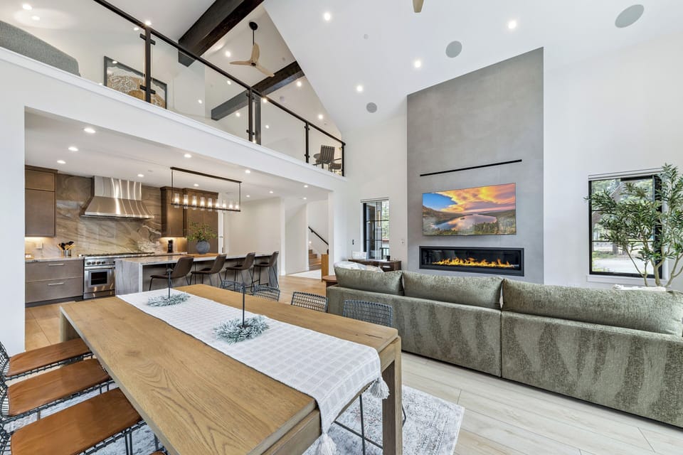 Picture yourself in this stunning open-concept space where soaring ceilings and warm textures invite you to gather, cook, and relax. Sunlight pours through expansive windows, illuminating your private loft retreat above.