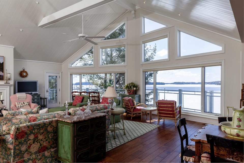 Antique floral sofas and wicker chairs gather around a green sideboard on rich hardwood floors.