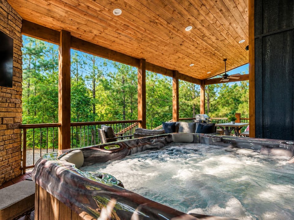 Private covered hot tub deck with forest views and cozy lounge seating