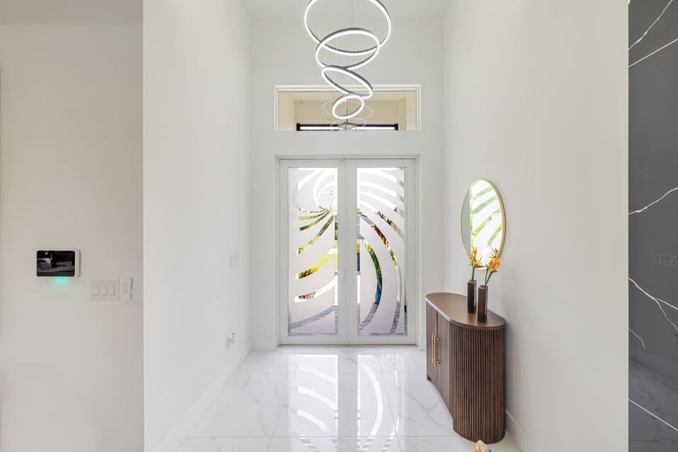 Welcoming foyer with a designer glass front door and soaring ceilings.