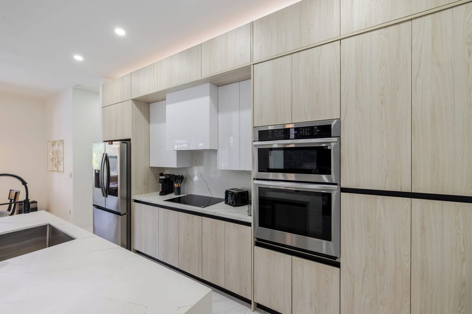 Sleek kitchen with light wood cabinetry and built-in stainless ovens.