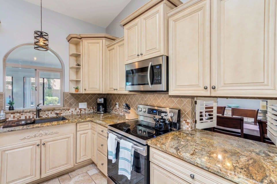 Open concept kitchen with stainless steel appliances, granite countertops, kitchen island with breakfast bar seating for 3, and coffee maker 