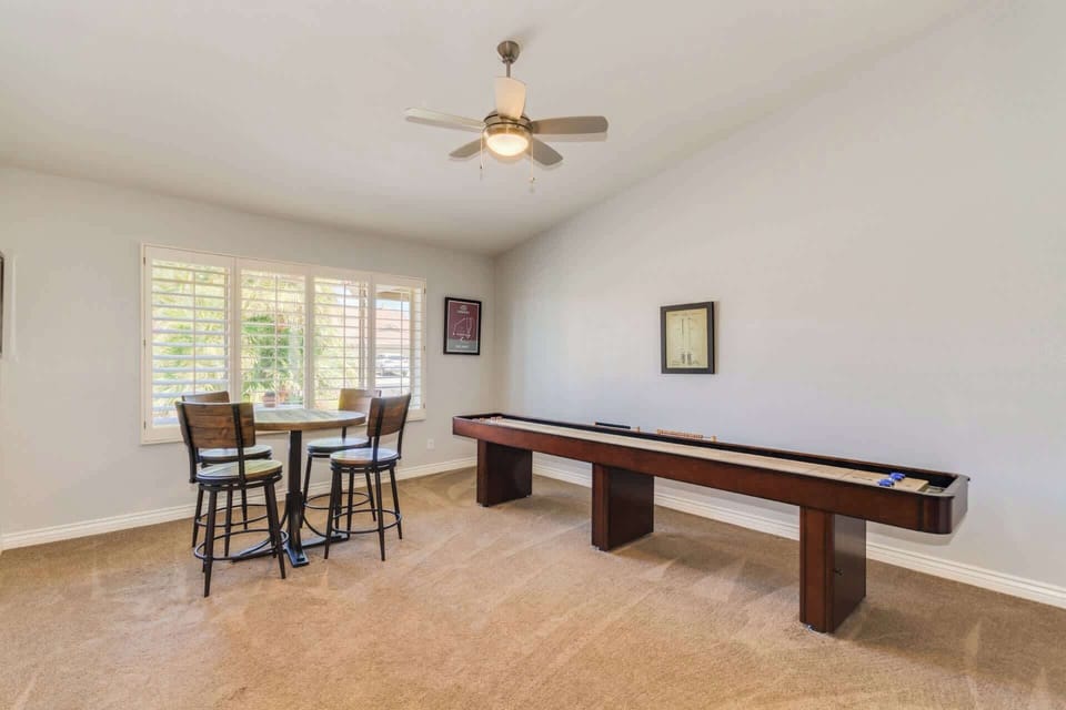 Game room with smart TV, shuffle board, high top table for 4, ceiling fan, and board games 