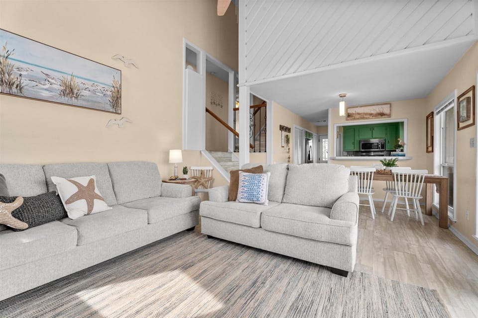 Open living area showcasing vaulted ceilings, comfortable seating, and seamless flow between the living room, dining area, and kitchen.