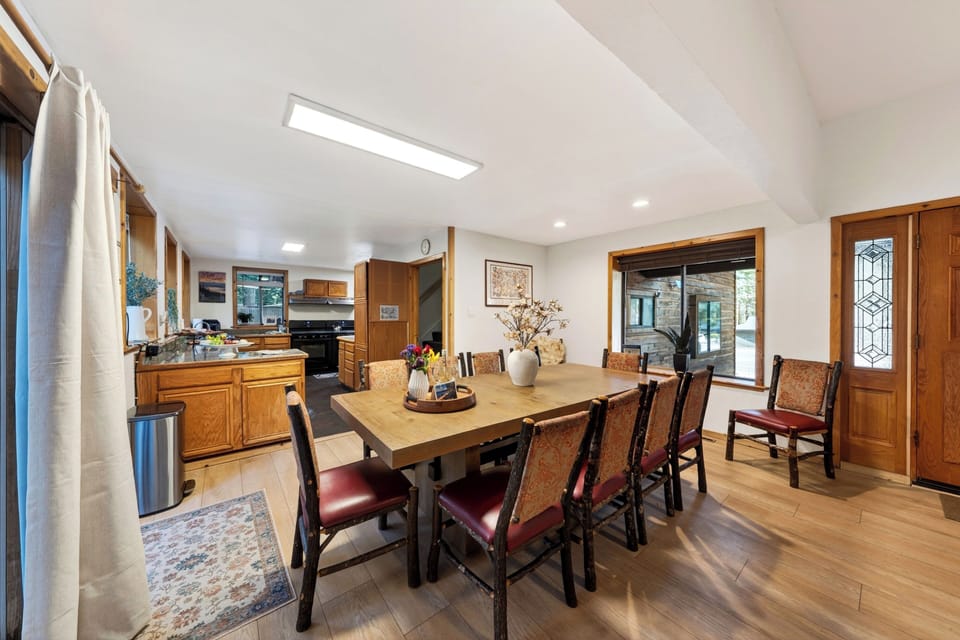 Grand dining room with a long wooden table, comfortable seating, and proximity to the kitchen.