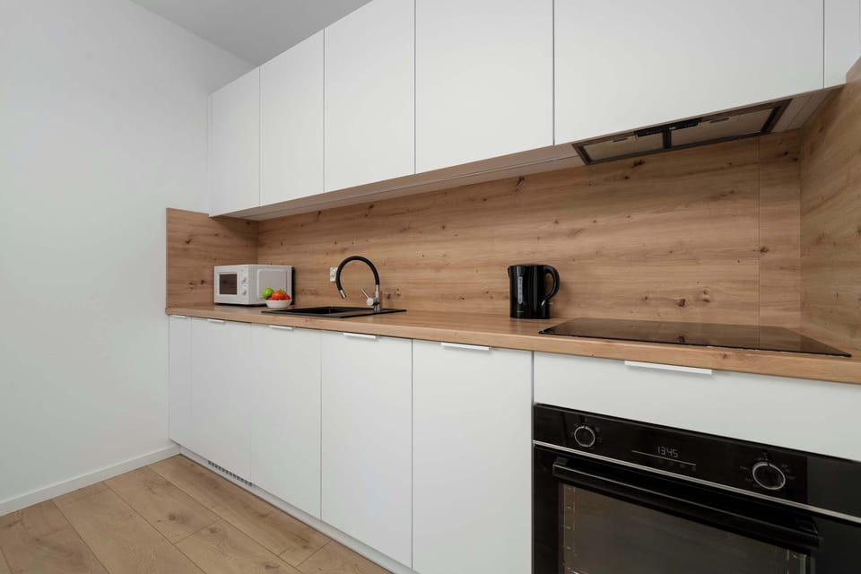 A detailed view of the kitchen counter highlights built-in appliances, including a black oven and a stovetop. A small microwave sits on the wooden countertop under white upper cabinetry.