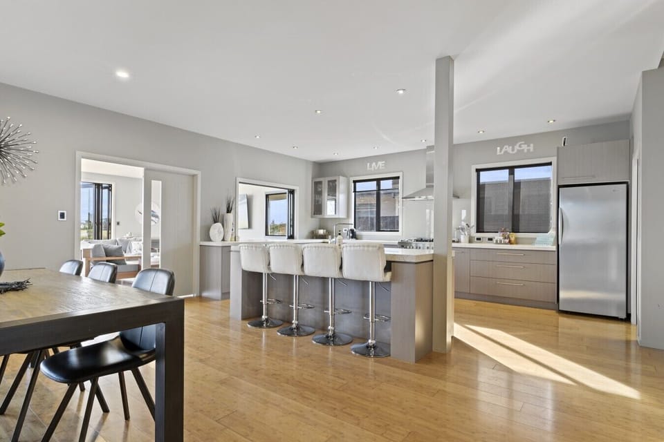 A generously designed open-plan kitchen, elegantly equipped with an oven, fridge, freezer, dishwasher, and a complete set of kitchen utensils and cutlery.