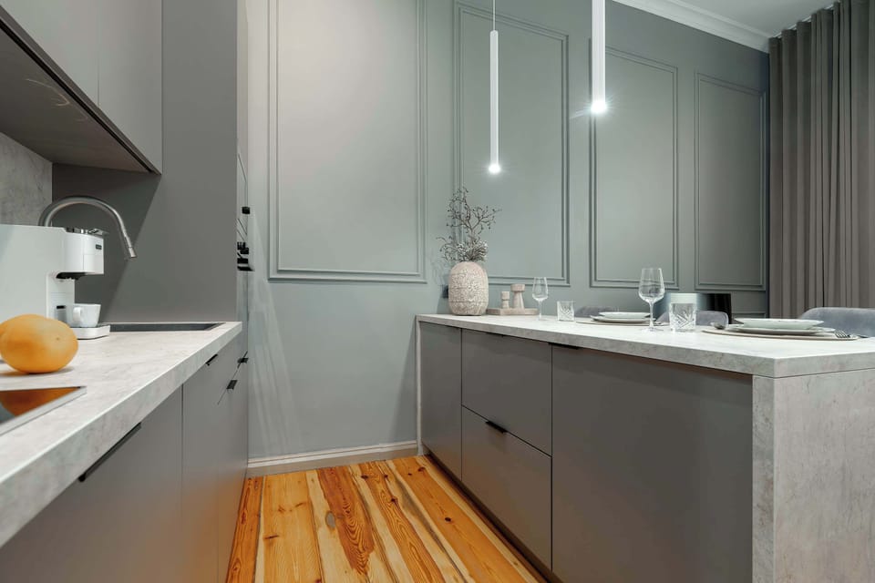 A bright kitchenette with an island and modern cabinetry. Wooden flooring adds warmth to the room.