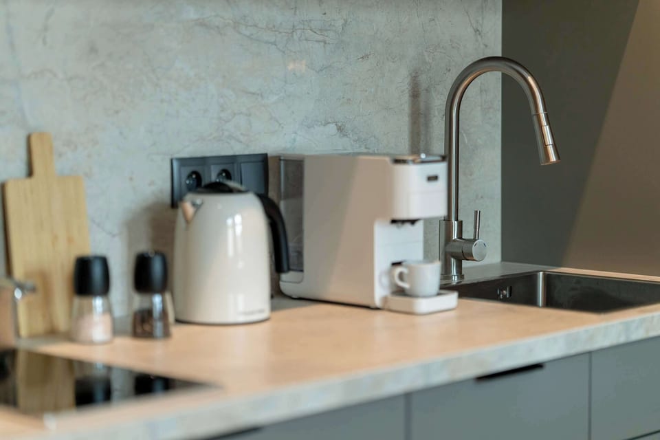 A kitchen countertop with a coffee machine, kettle, and sink. Functional and stylish workspace.