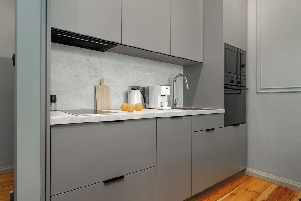 A modern kitchenette with grey cabinets and built-in appliances. Clean lines create a sleek look.
