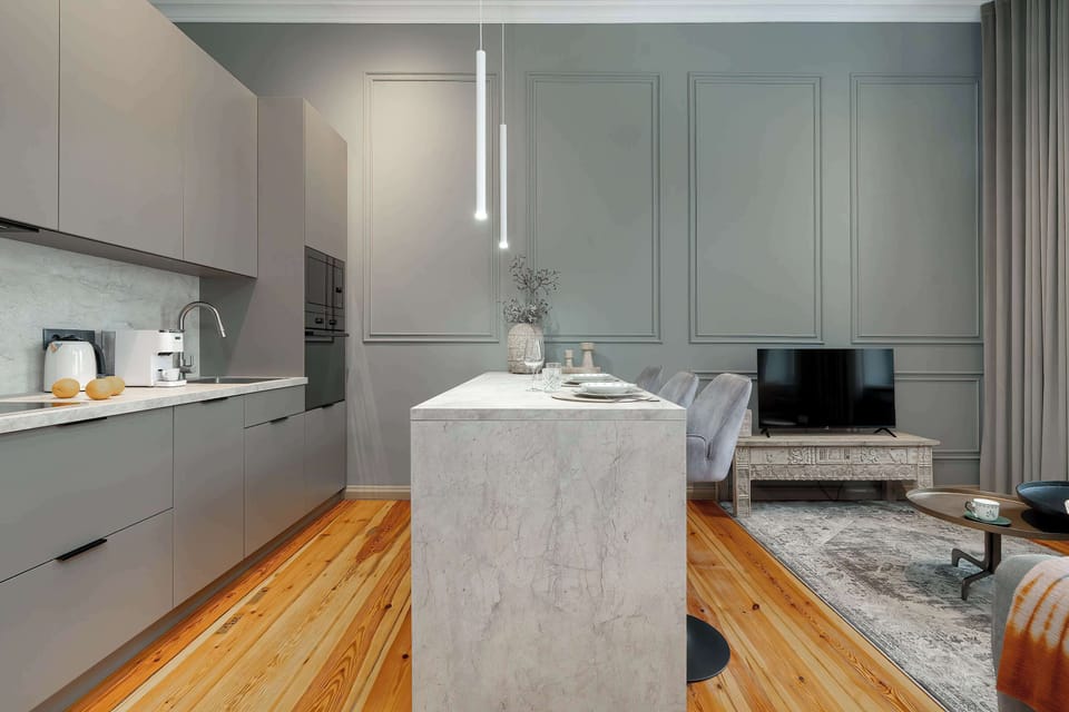 A contemporary kitchenette with grey cabinets and a central island. Warm wooden floors add character to the space.