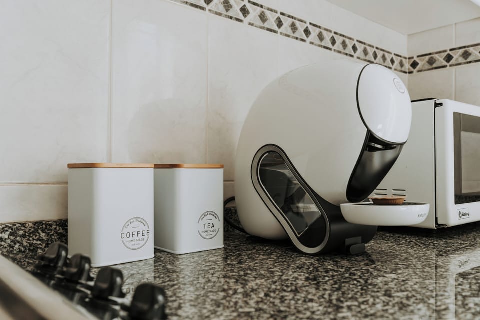 Sleek kitchen with capsule coffee bar, tea canisters, and microwave