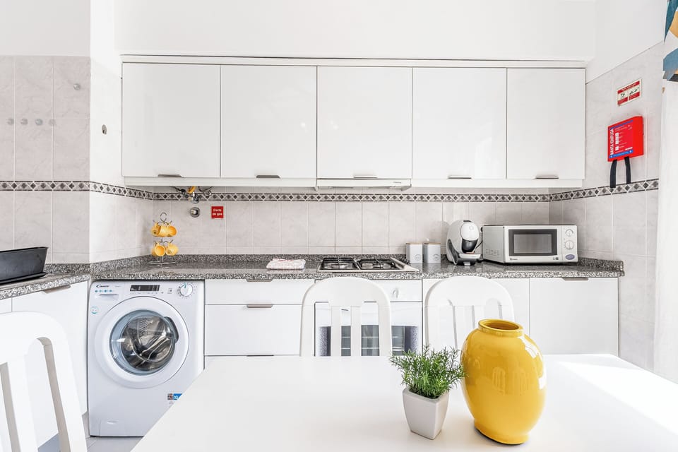Sunny, sleek kitchen with washer, microwave, coffee bar and dining table.