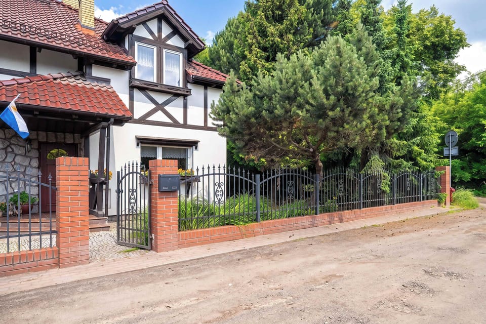 The exterior of a detached house with timber accents, fencing, and mature greenery surrounding the property.