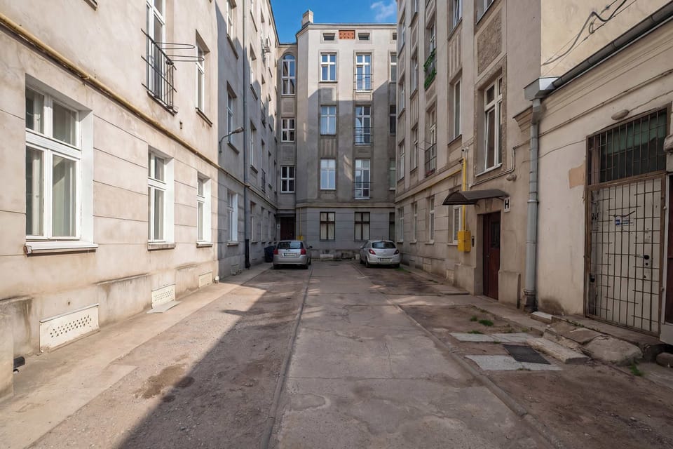 A narrow courtyard or street area between buildings with a paved walkway. The picture shows the exterior surroundings of the apartment building.