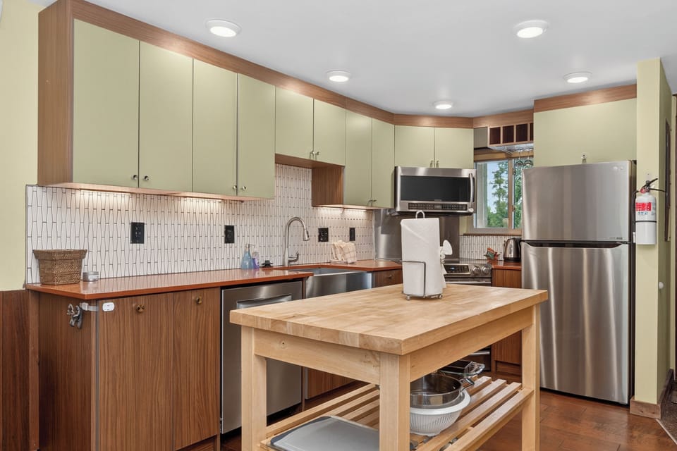 Your fully equipped kitchen awaits with stainless steel appliances, ample storage, a spacious center island, and modern tile backsplash—perfect for preparing home-cooked meals during your stay.