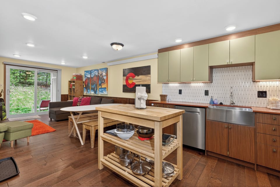 Step into your thoughtfully designed open-concept space where a fully equipped kitchen flows seamlessly into the living area. Sunlight pours through sliding glass doors, framing garden views and inviting you to relax in this warm, welcoming retreat.