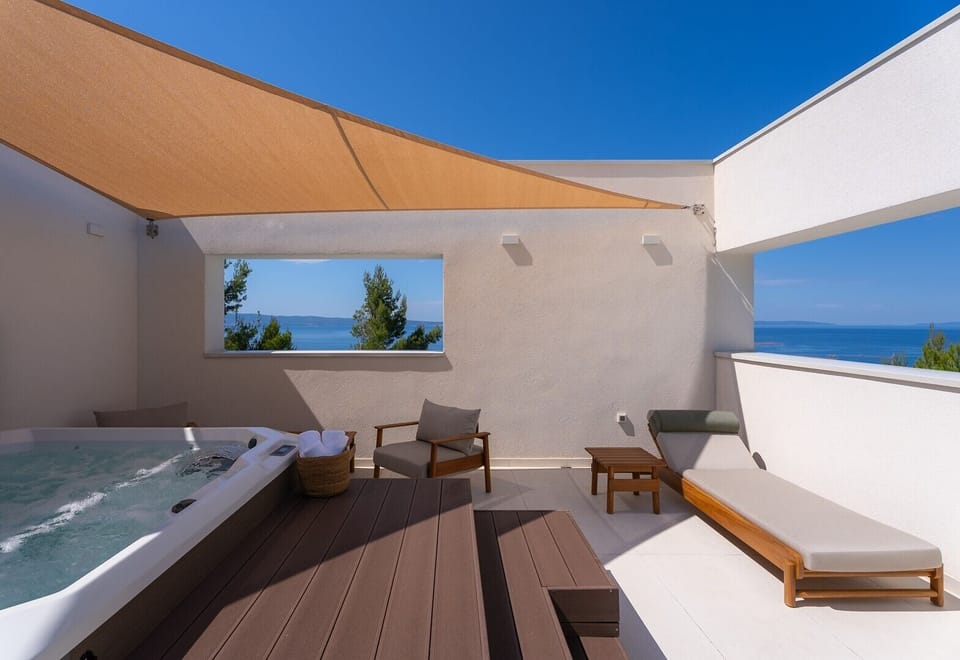 Rooftop wellness terrace with a private jacuzzi, shaded seating area, and open views of the sea, Split, and the islands