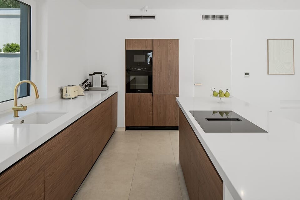 The clean design, warm wood finishes, and natural light create an elegant and functional space for preparing meals and gathering