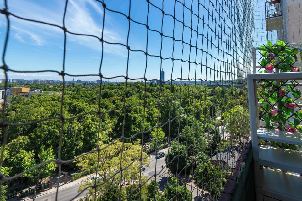 The balcony railing is securely fitted with a black safety net, providing peace of mind while enjoying the impressive, unblocked views of the surrounding green neighborhood.
