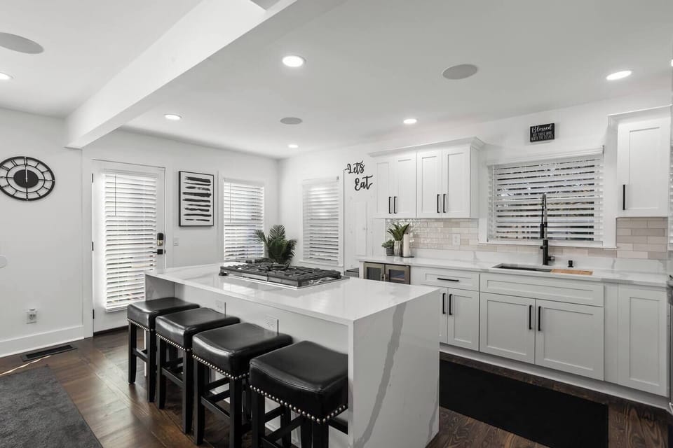 Bright, modern kitchen featuring a sleek gas stovetop, combo oven, and a beautiful quartz waterfall island with seating for 4. Perfect for cooking and socializing, this space is ideal for both business travelers and vacationers.