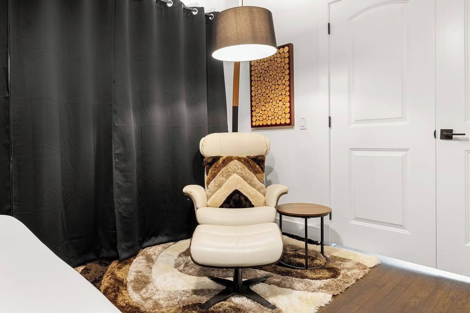 Cozy corner seating featuring a mid-century style armchair and stylish lamp, perfect for reading or relaxing. With modern decor and soft lighting, this space is ideal for winding down, offering a peaceful retreat for business or leisure travelers.