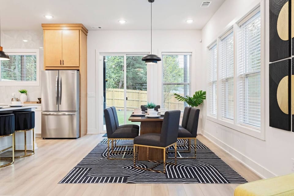 Bright and modern dining area with seating for four, gold-accented chairs, and large windows that fill the space with natural light. Enjoy family meals or morning coffee steps away from the kitchen and backyard patio.